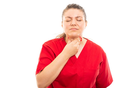 年轻的医疗护士穿着红色穿着红色的擦洗，显示喉咙疼痛的手势，隔离在白色背景上，带有复印空间广告区域