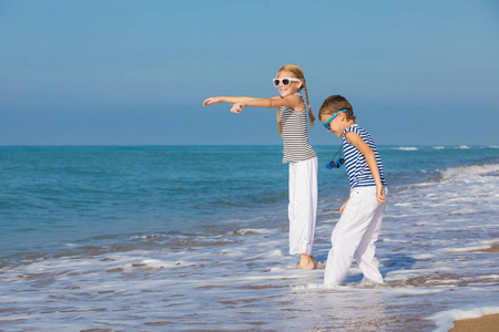 两个快乐的小孩子在海滩上玩耍. 他们穿着水手背心.