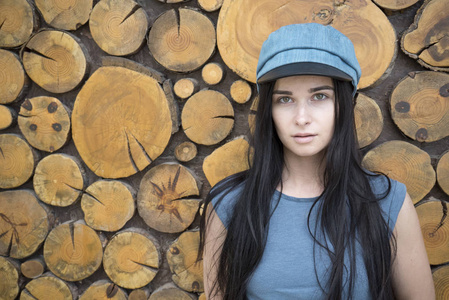 木制背景上的女孩肖像。戴着蓝色帽子的女孩。戴帽子的女孩的肖像。美丽的黑发