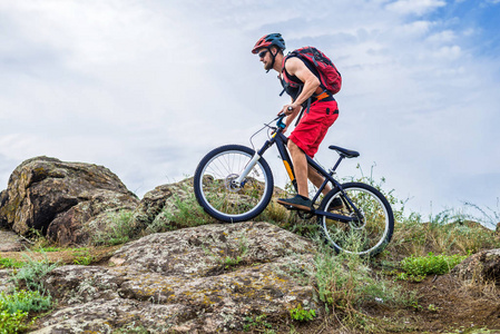骑着山地自行车沿着岩石往下走，这是一种活跃的生活方式。极限骑自行车对抗蓝天，自由空间，为您的文字。