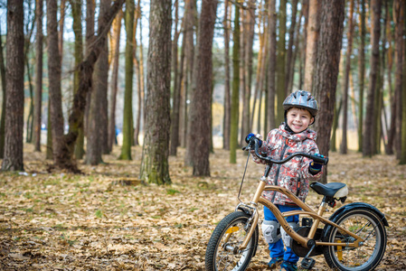 快乐的3到5岁的男孩在秋天的森林里玩，在美丽的秋天骑自行车。 活泼的孩子戴着自行车头盔。 安全运动休闲与儿童概念