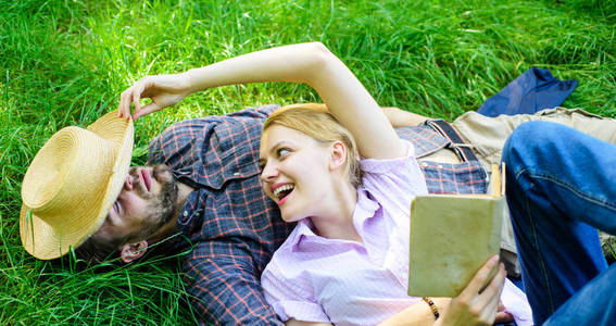 浪漫夫妇家庭享受休闲与诗歌或文学草背景。 浪漫约会的情侣灵魂伴侣。 男人和女孩躺在草地上放松。 恋爱中的夫妇花闲暇时间看书。