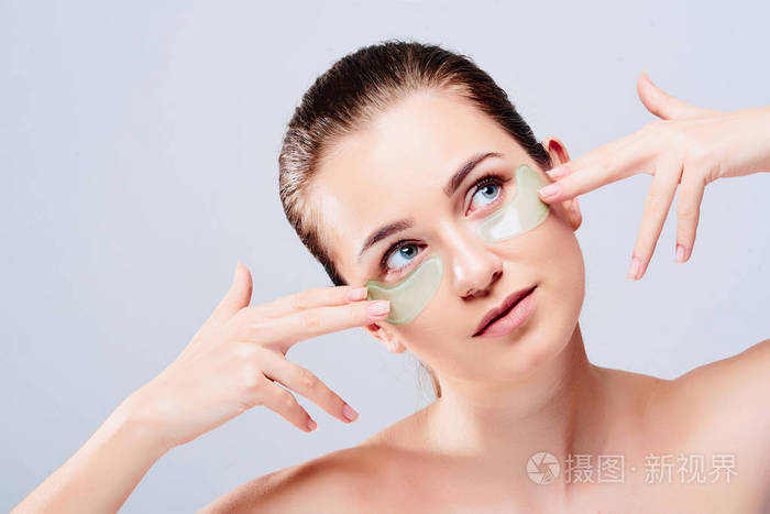 美丽的年轻女性模特的肖像与自然化妆和眼部护理水凝胶贴片与透明质