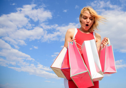 女人红裙背着一群购物袋的蓝天背景.女孩满意购买.