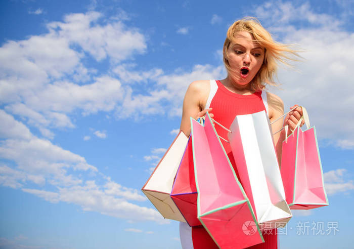 女人红裙背着一群购物袋的蓝天背景.女孩满意购买.