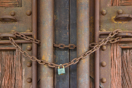 带有重金属环的大钥匙挂在生锈污渍的铁门上.照片