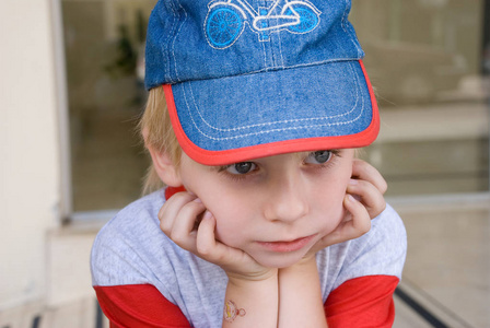 可爱的金发男孩的肖像,双手托着下巴,望着远方照片