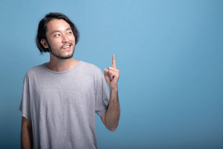 年轻的留胡子的男人用蓝色背景指着手指.