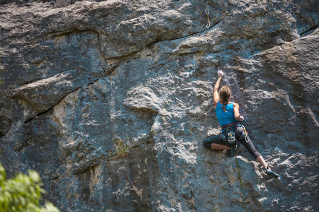 女孩爬上岩石。 登山者正在训练攀登岩石。 一个强壮的运动员克服了一条艰难的攀登路线。 极端的爱好。 一个女人在大自然中参加运动。