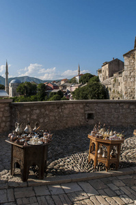 波斯尼亚和黑塞哥维那2018年7月5日一张小桌子，上面有典型的铜茶和咖啡套，供出售，并在背景上看到莫斯塔尔的天际线，背景是Ko