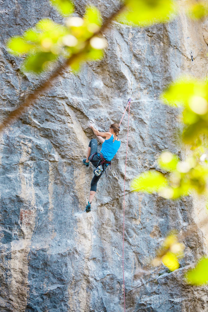 登山者正在训练攀登岩石一个强壮的女孩克服了一条艰难的攀爬路线积极