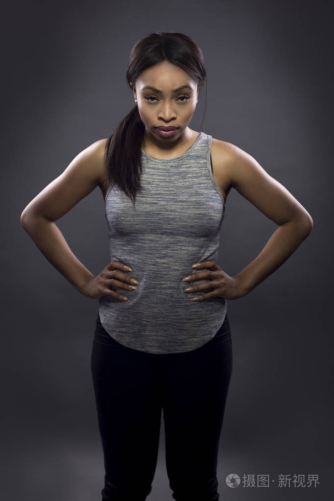 黑色健身教练或运动员在黑暗的背景下冒充一个坚韧的女人.