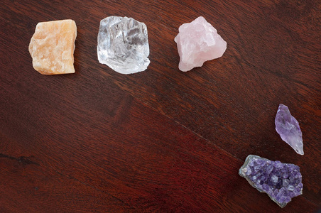 木桌上的愈合晶体，包括透明石英香茅碱方解石紫晶石和玫瑰石英。 宝石被用来治疗能量，良好的振动，同时冥想或冥想。