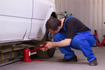 机械师在汽车服务中使用千斤顶照片