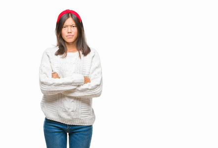 年轻的亚洲女人穿着冬天的毛衣，在孤立的背景怀疑和紧张，不赞成的表情在脸上交叉的手臂。消极的人。