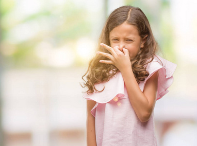 布鲁内特西班牙裔女孩穿着粉红色的连衣裙,闻着一些臭而恶心的东西
