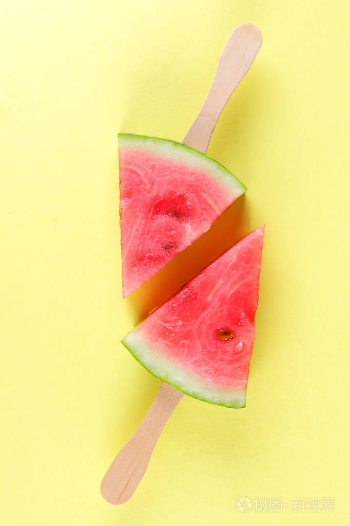 西瓜流行艺术. 一块西瓜在黄色背景上的棍子上. 一种极简风格的天然甜