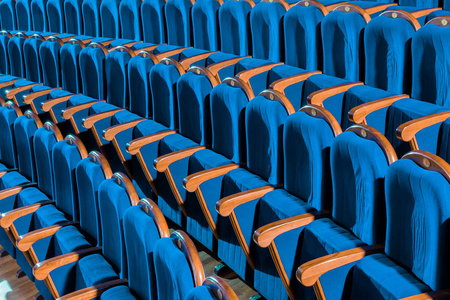 礼堂里有带木扶手的蓝色毛绒椅子。 剧院里空荡荡的礼堂。