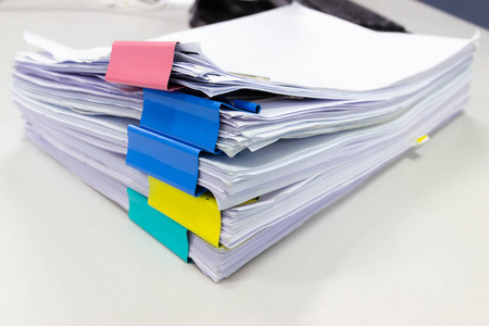 将文件文件堆放在档案文件中，办公室办公桌上有回形针，商业概念。