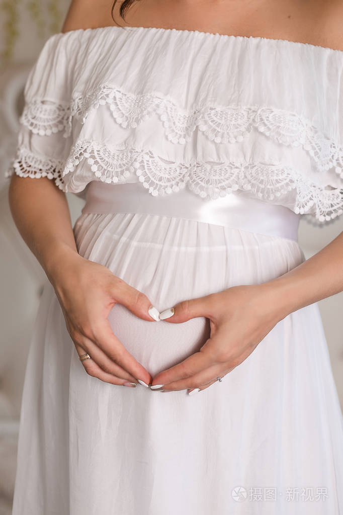 年轻的孕妇把手放在她肿胀的肚子上爱情观念