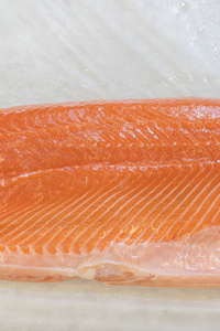 超市柜台上冰上鲑鱼片。 超市冰上的红鱼片。 海洋健康食品。 垂直照片。