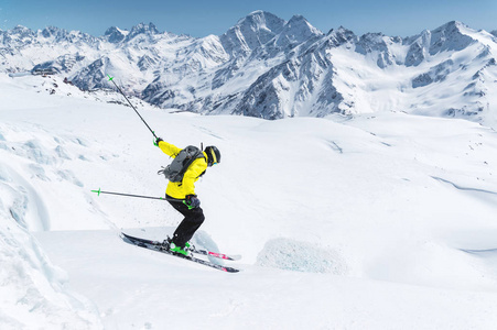 一个滑雪运动员在充分的体育设备跳入峭壁从山顶在蓝色天空和高加索雪山的背景下。Elbrus 地区。俄罗斯