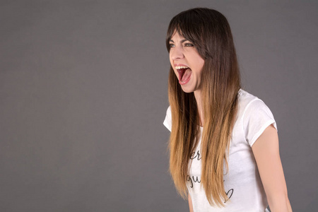 一个年轻的女人大声喊叫.那女孩用狂野张开的嘴尖叫照片