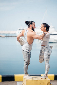 年轻美丽的夫妇做伸展运动在海洋码头