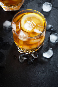 冷冰茶与柠檬和冰块在黑石背景复制空间顶部视图。 冰镇夏日饮料。