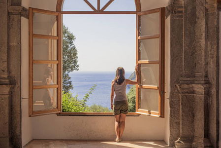 一个大开着的窗户上的年轻女人.夏季摘要照片.照片