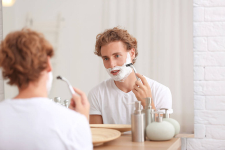 年轻的帅哥在浴室刮胡子