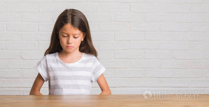 年轻的西班牙裔孩子坐在家里的桌子上沮丧,担心痛苦,哭泣,愤怒和害怕.