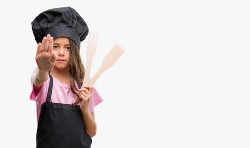 黑黑肤色的西班牙裔女孩穿着厨师制服，张开手做停止标志，严肃而自信的表情防御手势