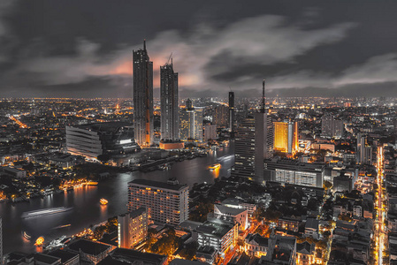 曼谷的夜晚生活在黑暗的色调中，照亮了摩天大楼上的城市景观
