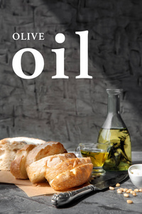 灰色背景上带新鲜面包的橄榄油瓶