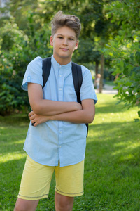 夏天公园里带着蓝色衬衫背包的可爱男孩。 回归学校教育理念