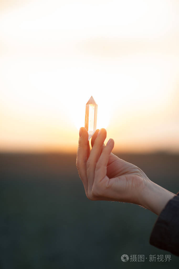 美丽的女人手里拿着小石英晶体在阳光下愈合水晶概念拍摄可以作为背景