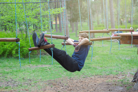 非常可爱的年轻运动，苗条和勇敢的男孩在冒险绳公园。 他将应对所有挑战