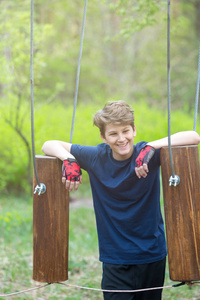 运动可爱的小男孩来到冒险绳公园，在他的暑假或春季假期玩得很开心