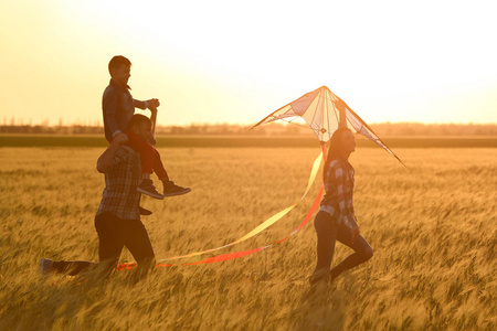 幸福的家庭在日落时在田野里放风筝