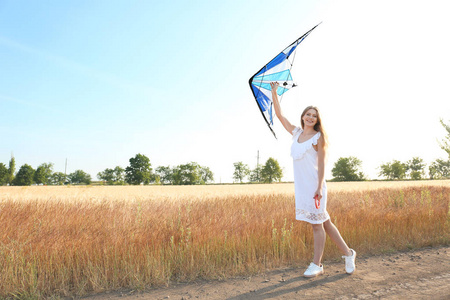 美丽的年轻女子在田野里放风筝