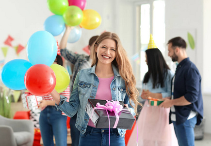 有生日礼物和气球的年轻女子在室内聚会