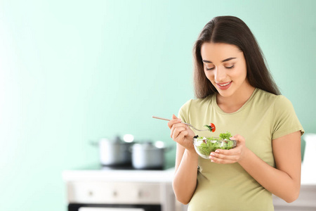年轻孕妇在厨房吃新鲜蔬菜沙拉