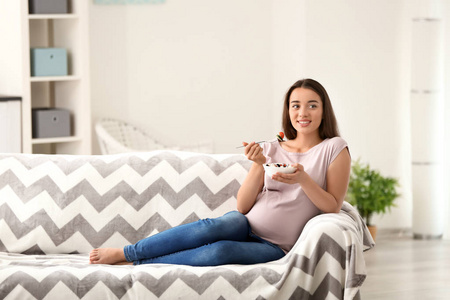 年轻孕妇在家吃健康沙拉