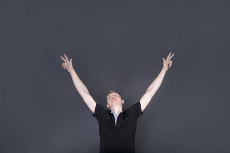 开朗的金发男性举起双手,眼睛充满了幸福.