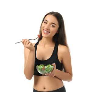 年轻的运动女性，白色背景的新鲜蔬菜沙拉
