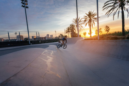 一个年轻人在夕阳下的碗里跳他的BMX。