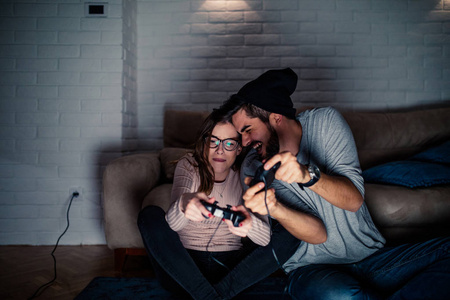 年轻夫妇在家玩电子游戏时竞争的照片。