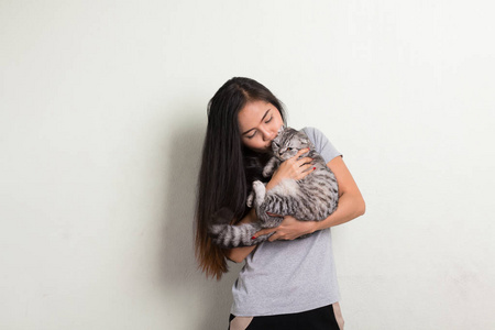 年轻快乐美丽的亚洲女人亲吻可爱的猫