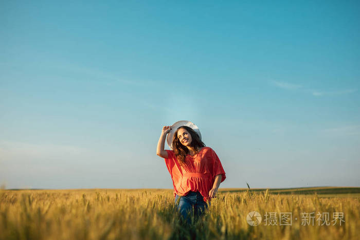一个带帽子的年轻女人在田野里微笑的照片。